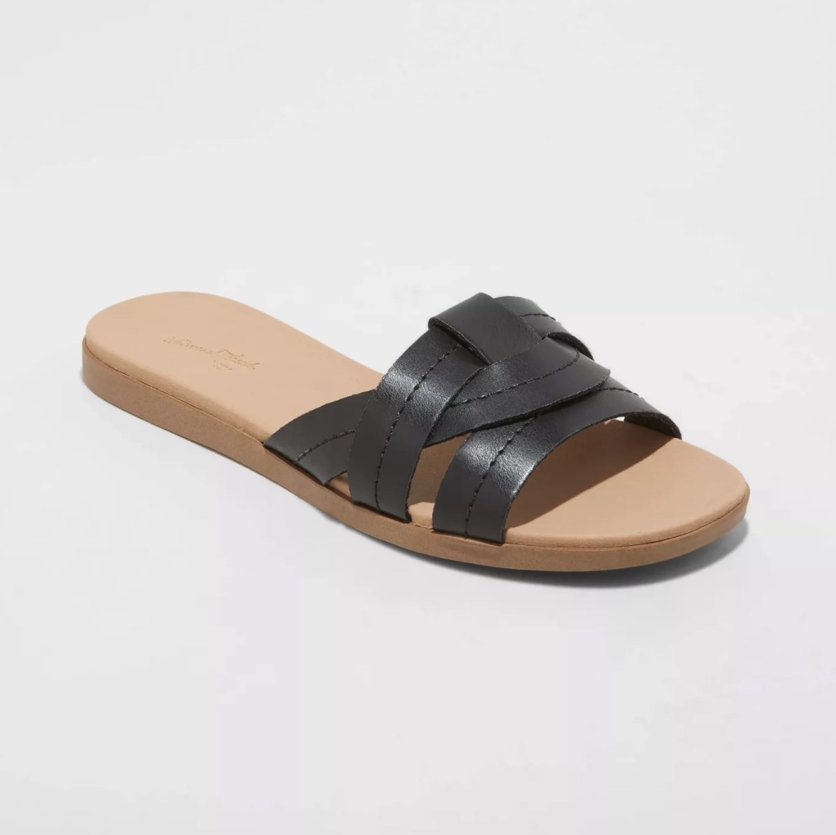 The tan sandals have three overlapping black straps over the toes