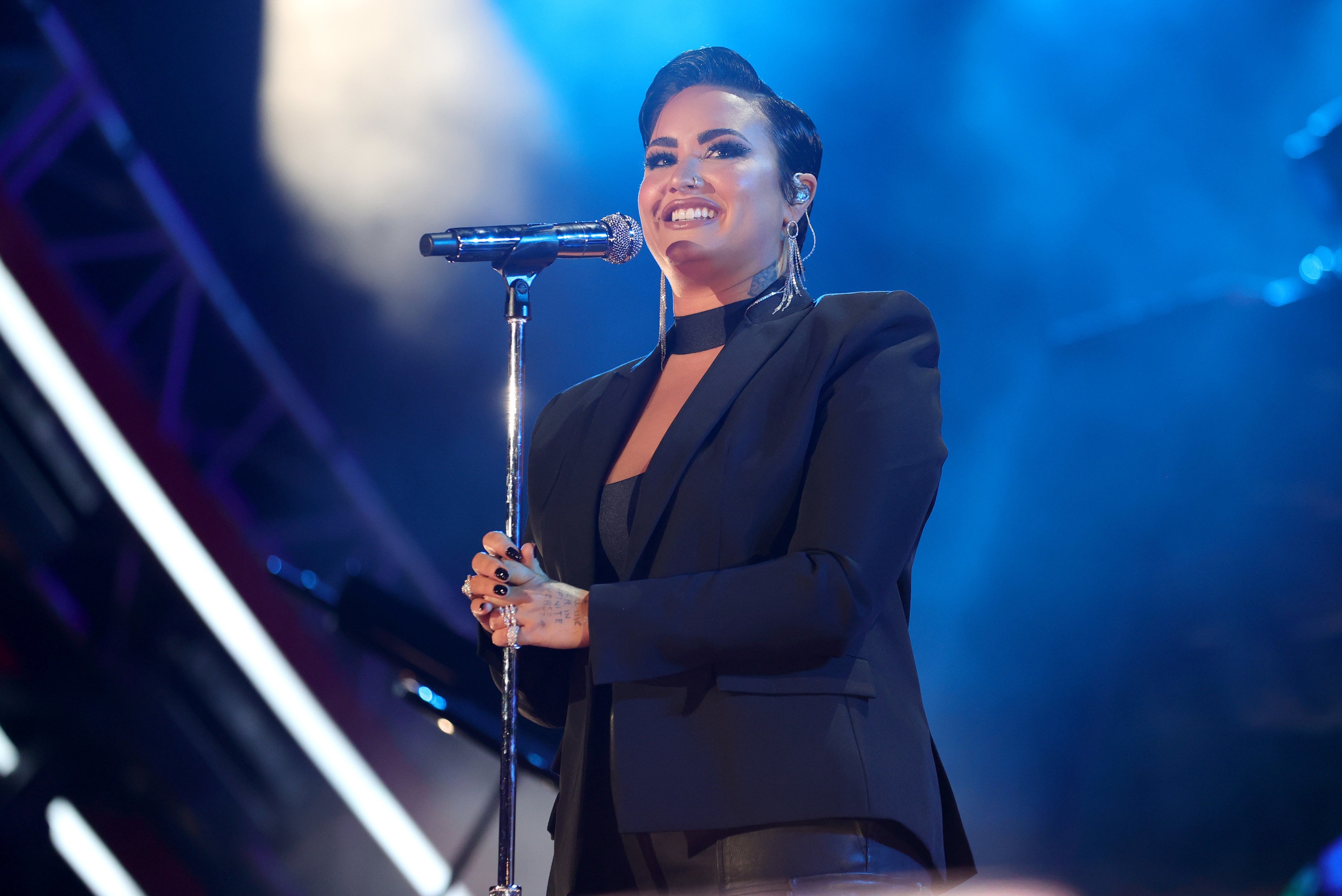 Demi smiles while gripping a microphone stand