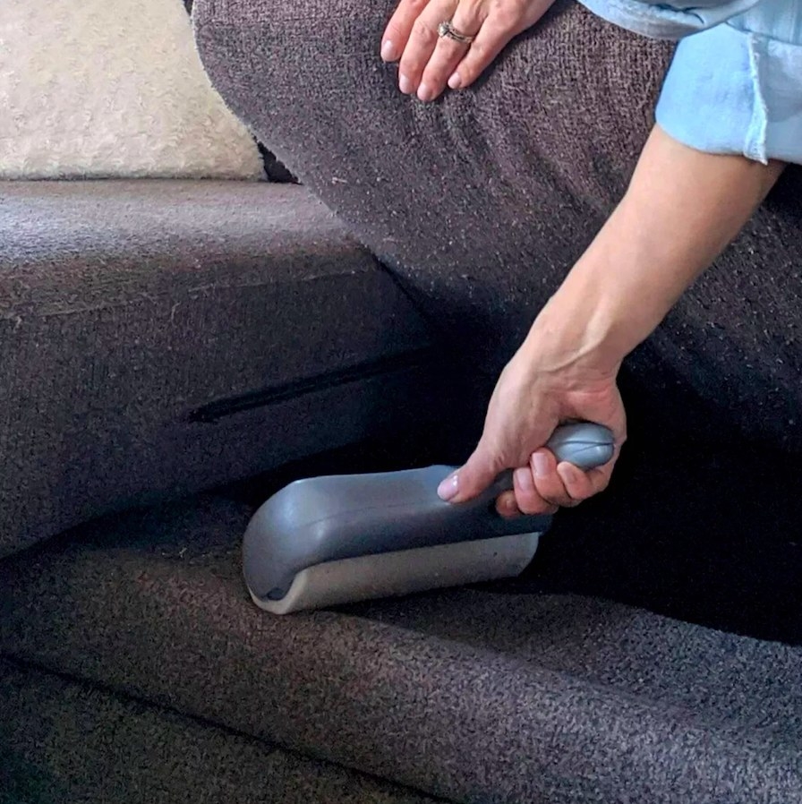 Model using lint roller under couch cushion