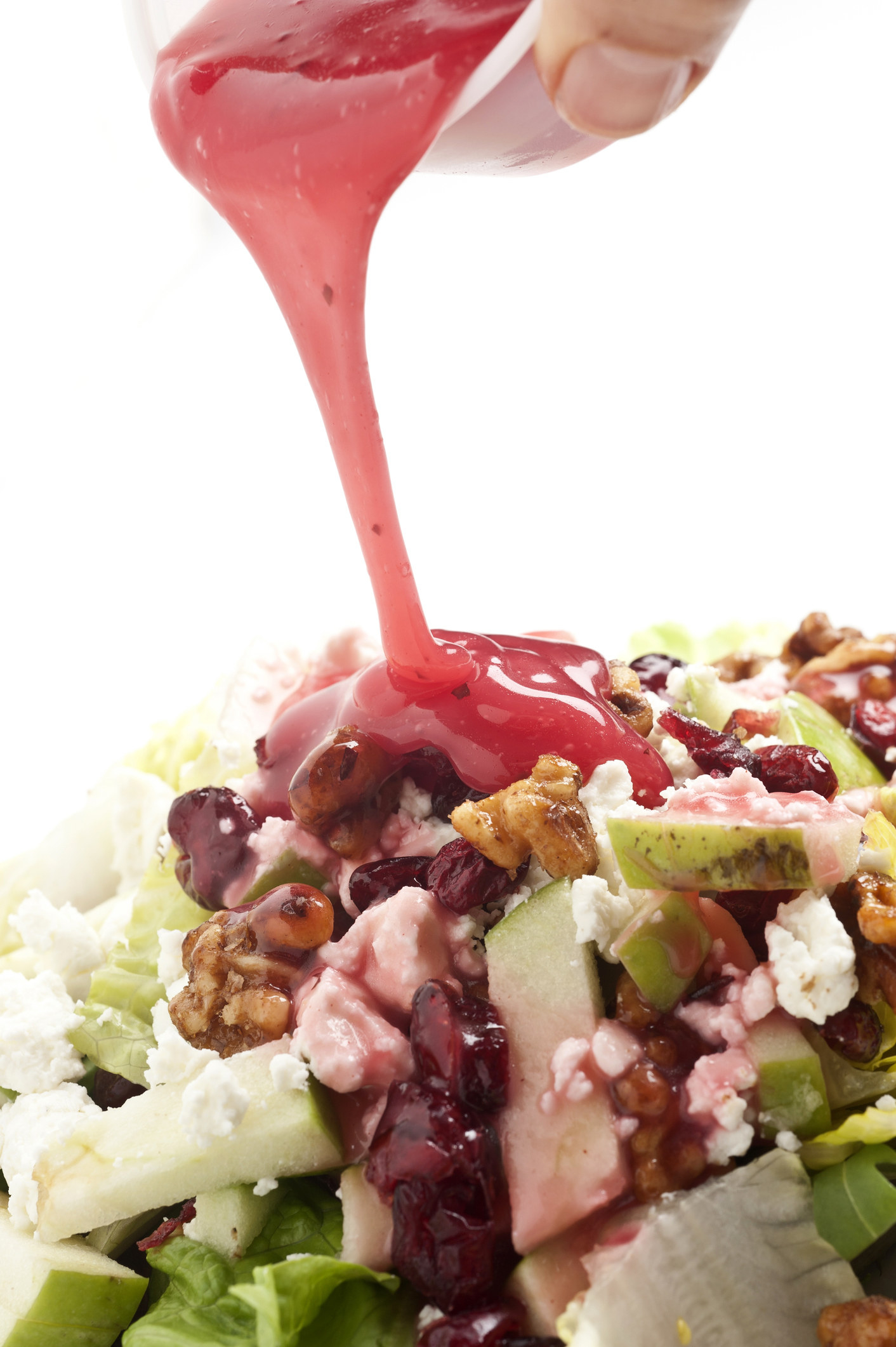 Coating a salad with pink dressing.
