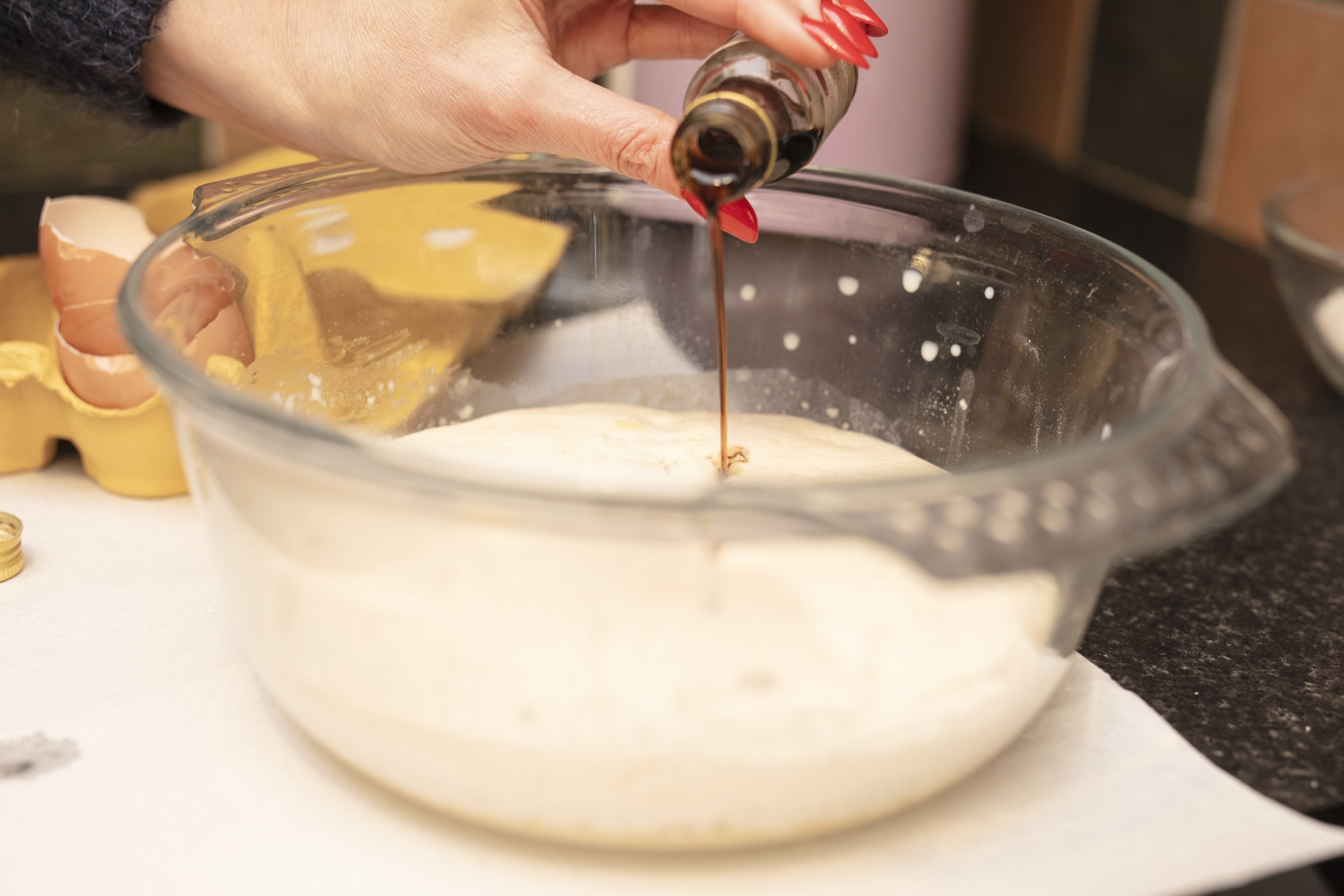 Pouring vanilla extract into a bowl of batter.