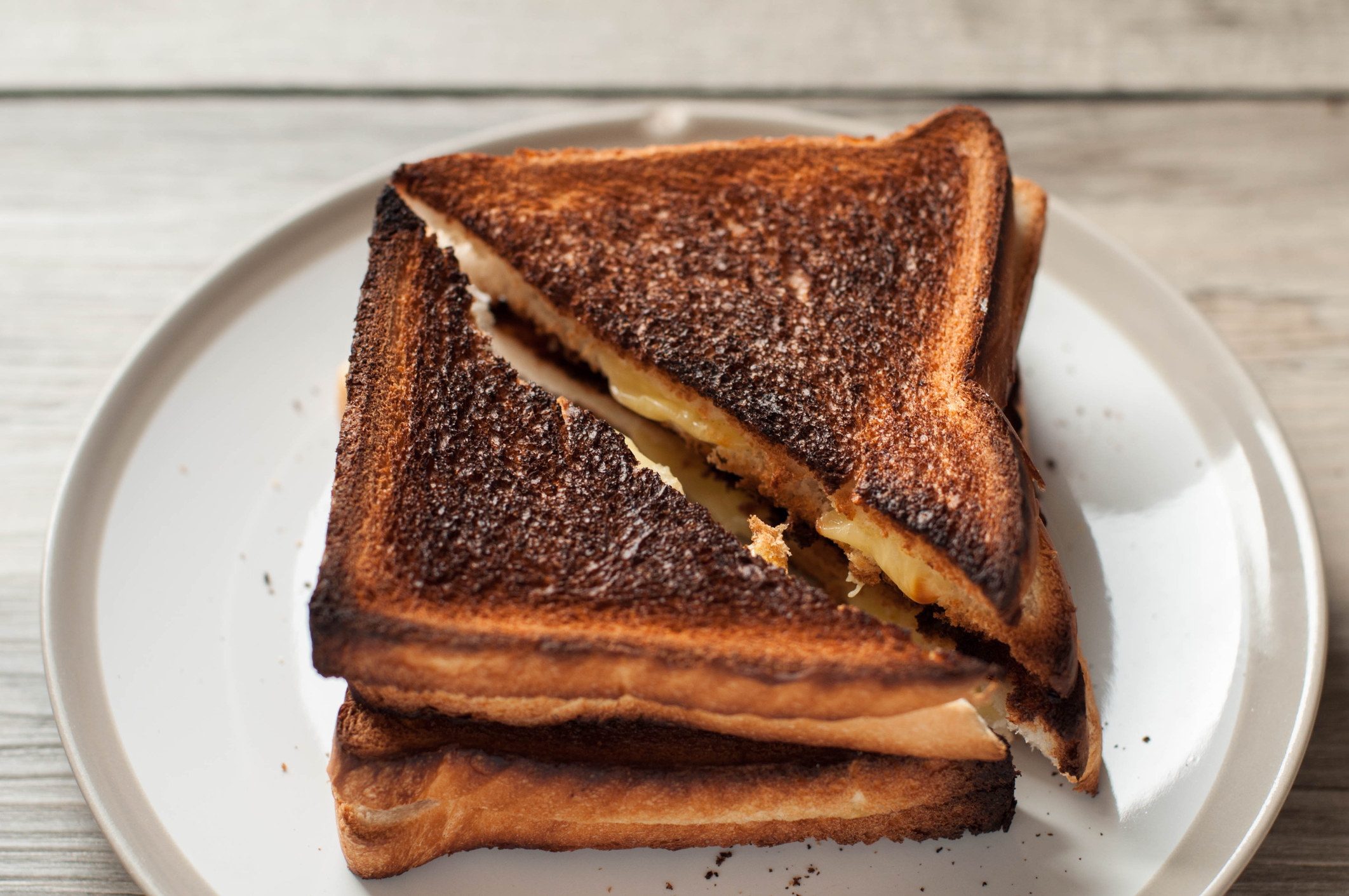 Still life of burnt toast with cheese on a wooden table.