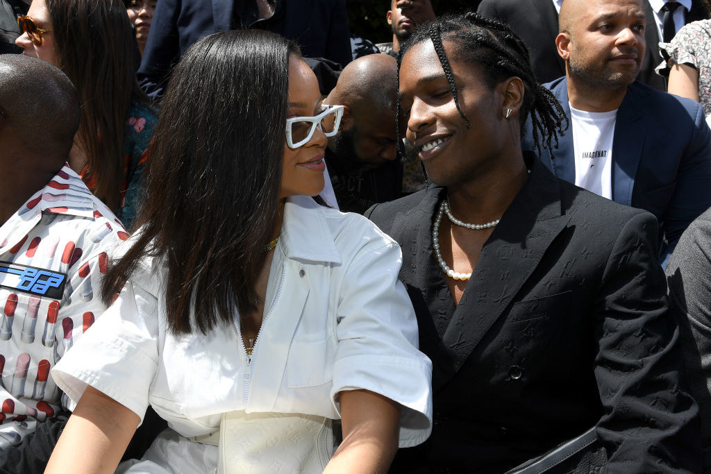 she has oversized geometric sunglasses, and he has a pearl necklace