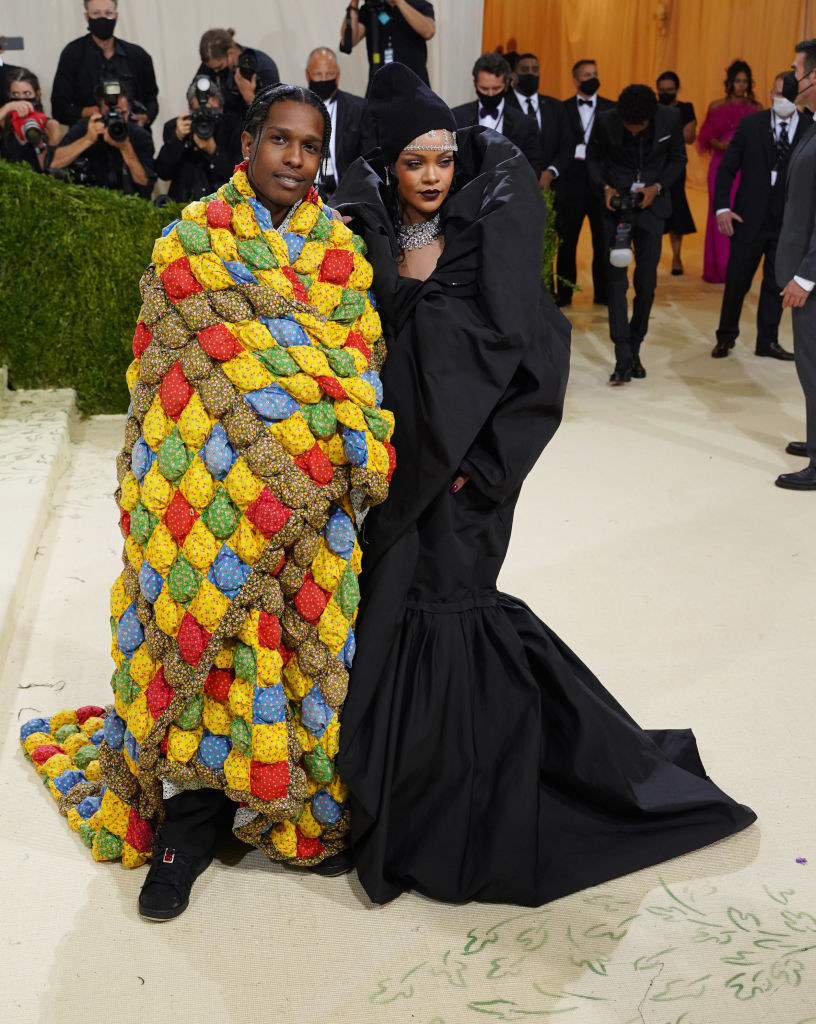 he&#x27;s wrapped in a colorful quilt, and she has a dark coat with a ruffled collar and a sparkly head chain