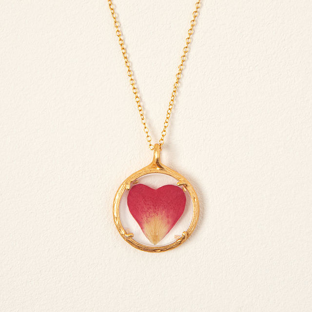 Close-up of the gold necklace with a heart-shaped rose petal pendant