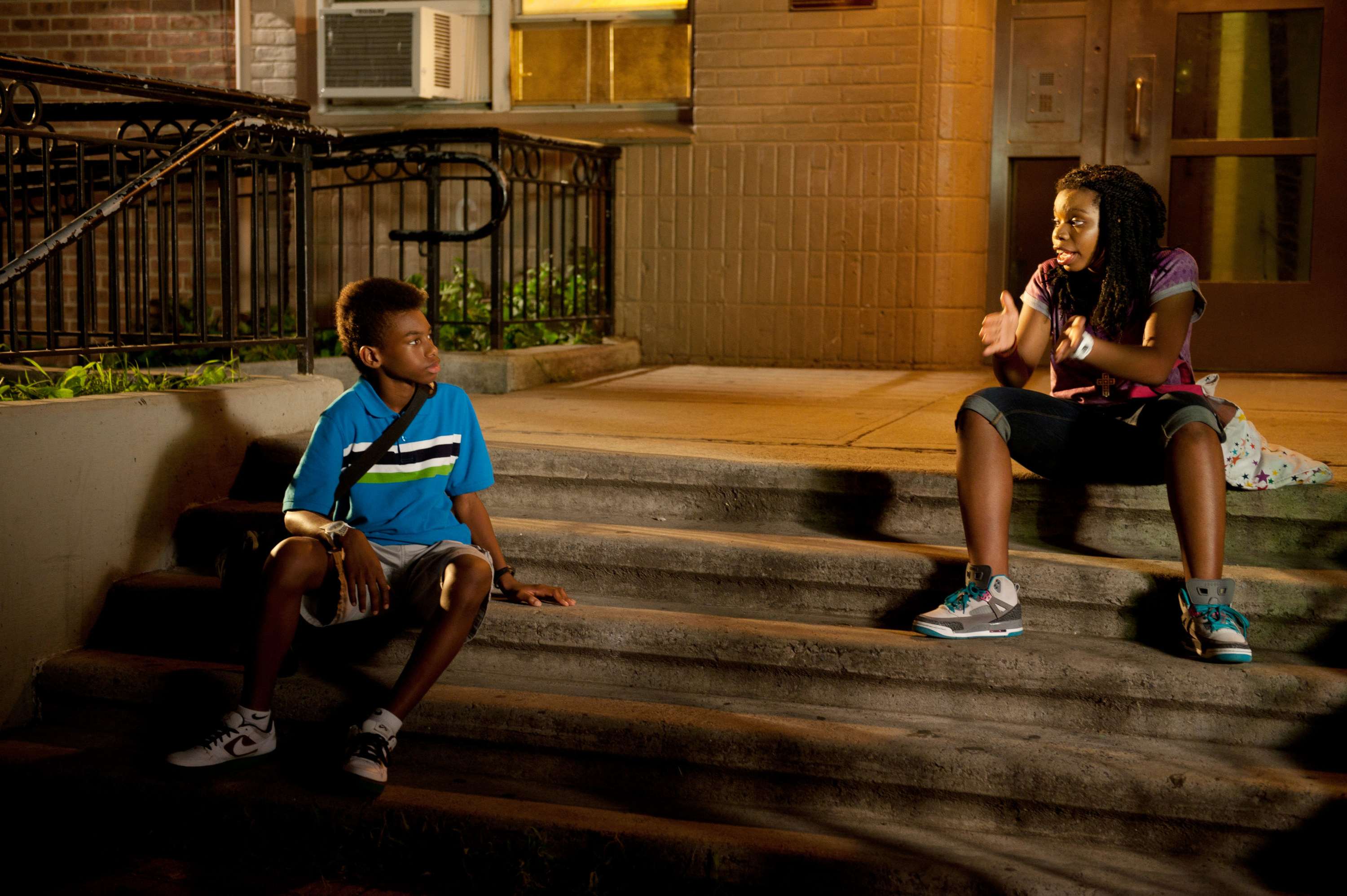 two children sit on a stoop and talk