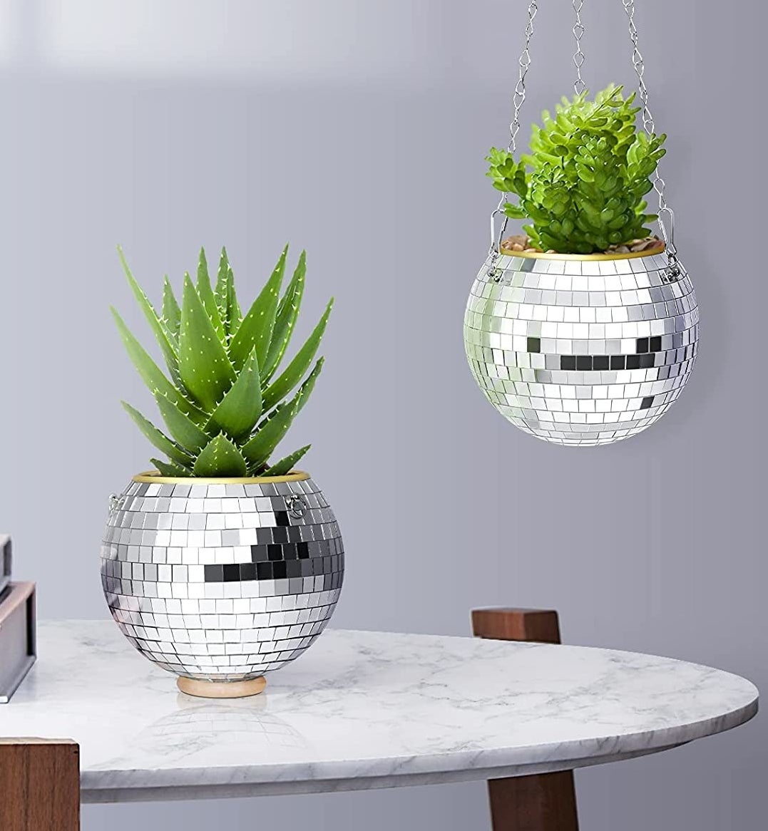 The disco ball planter sitting on a table and also hanging
