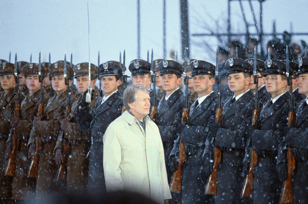 Jimmy Carter walking past a line of guards at the Warsaw airport in 1977