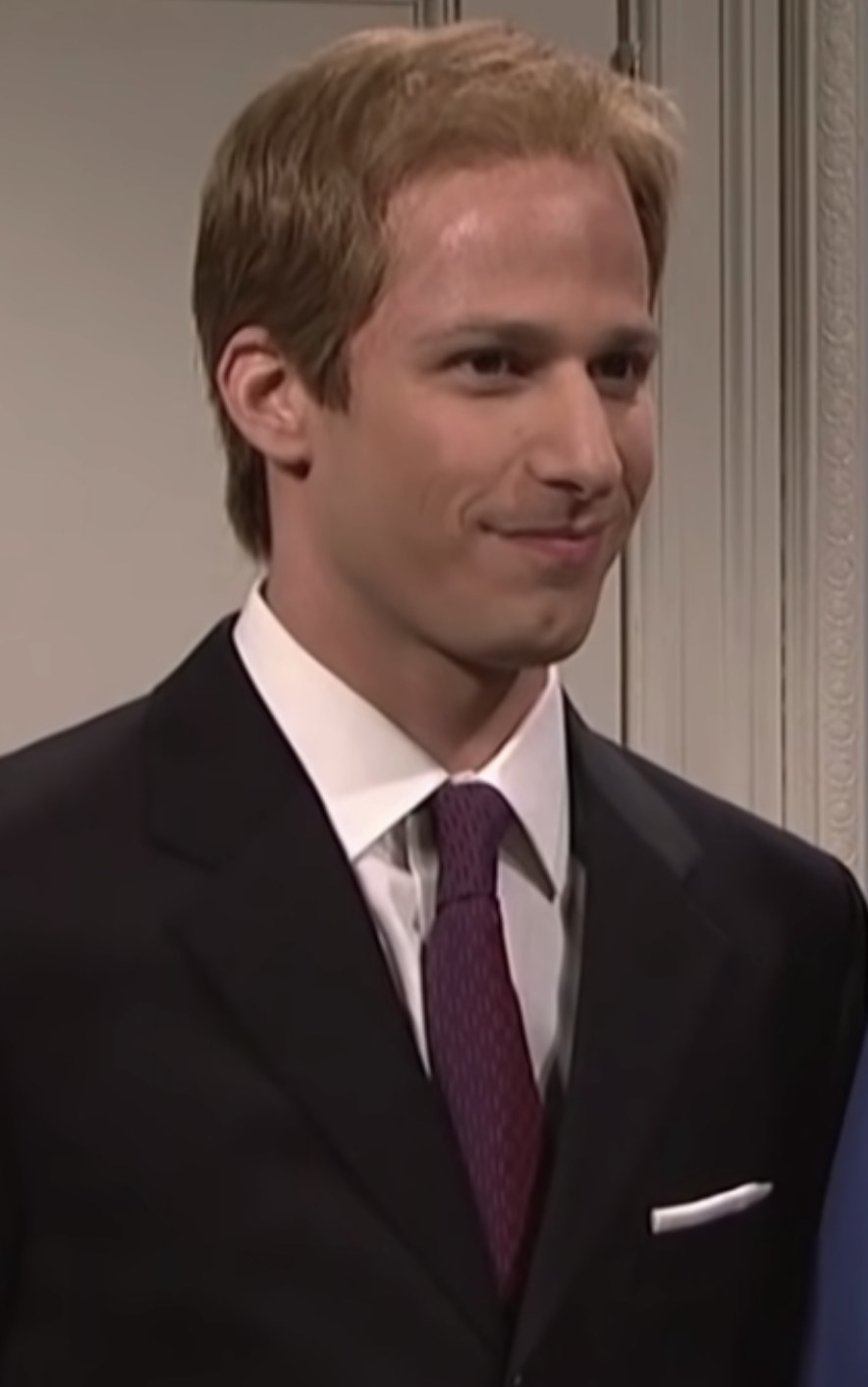 Samberg wearing a suit and tie and a Prince William-like hairdo