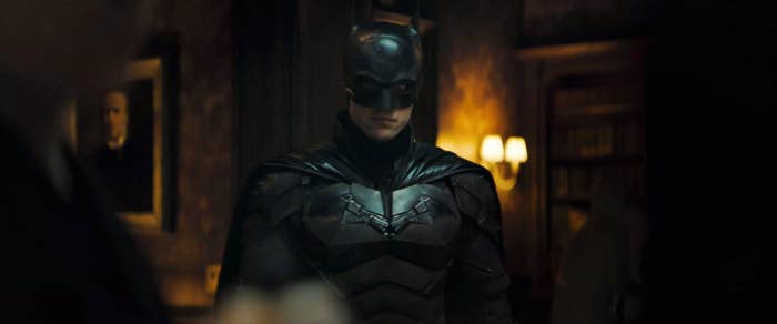 Robert in The Batman costume standing in the middle of a darkly-lit room