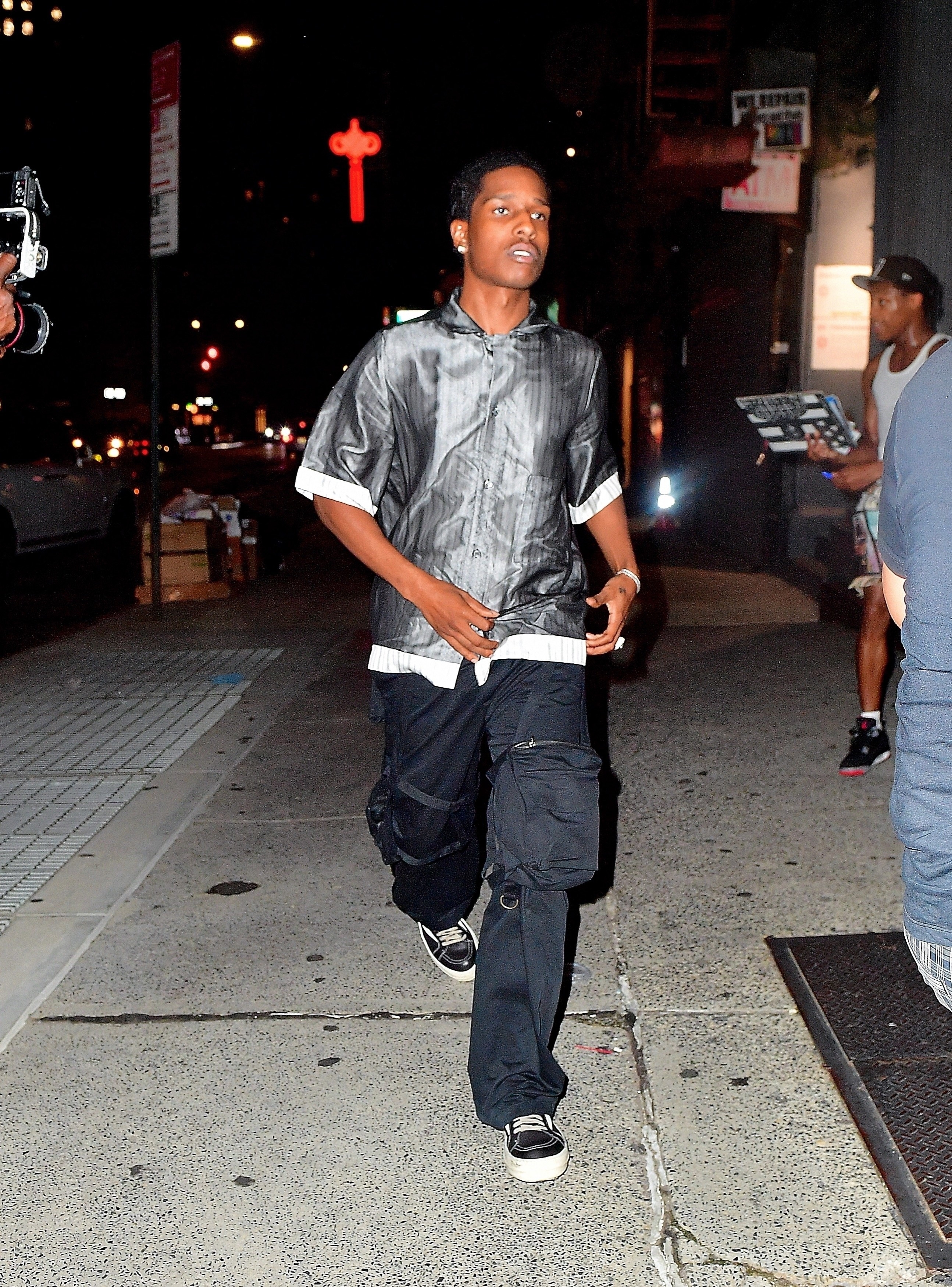 Rocky wears loose-fitting pants and a shiny button-up shirt