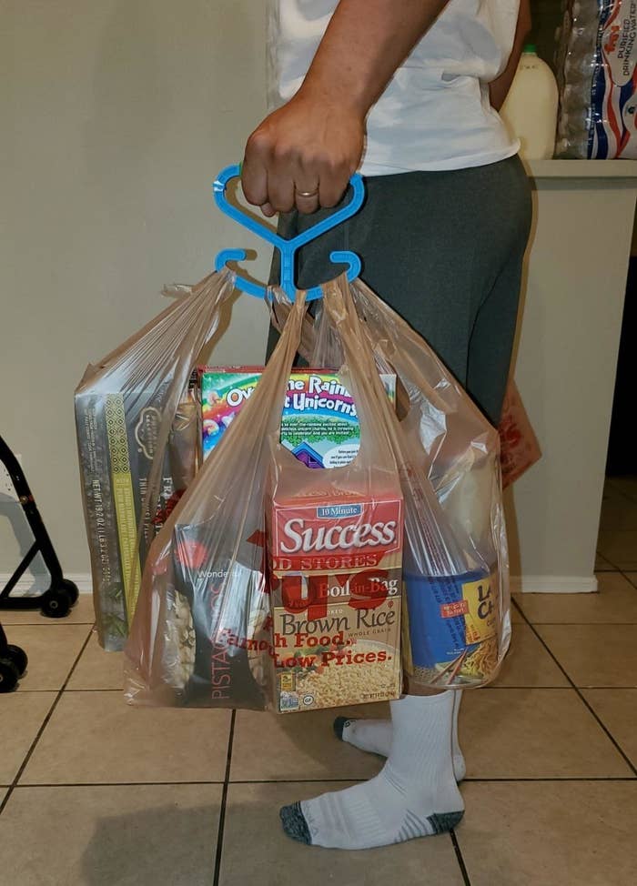 reviewer holding several bags of groceries using the grocery bag holder