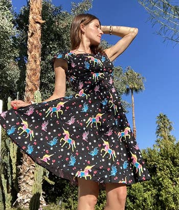 reviewer wearing the black dress with colorful unicorns on it