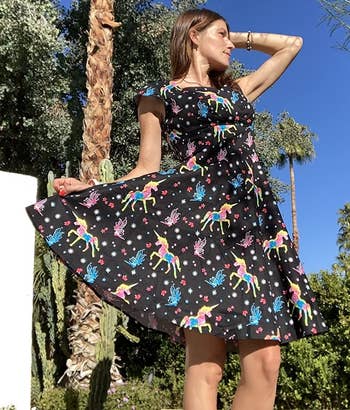 reviewer wearing the black dress with colorful unicorns on it