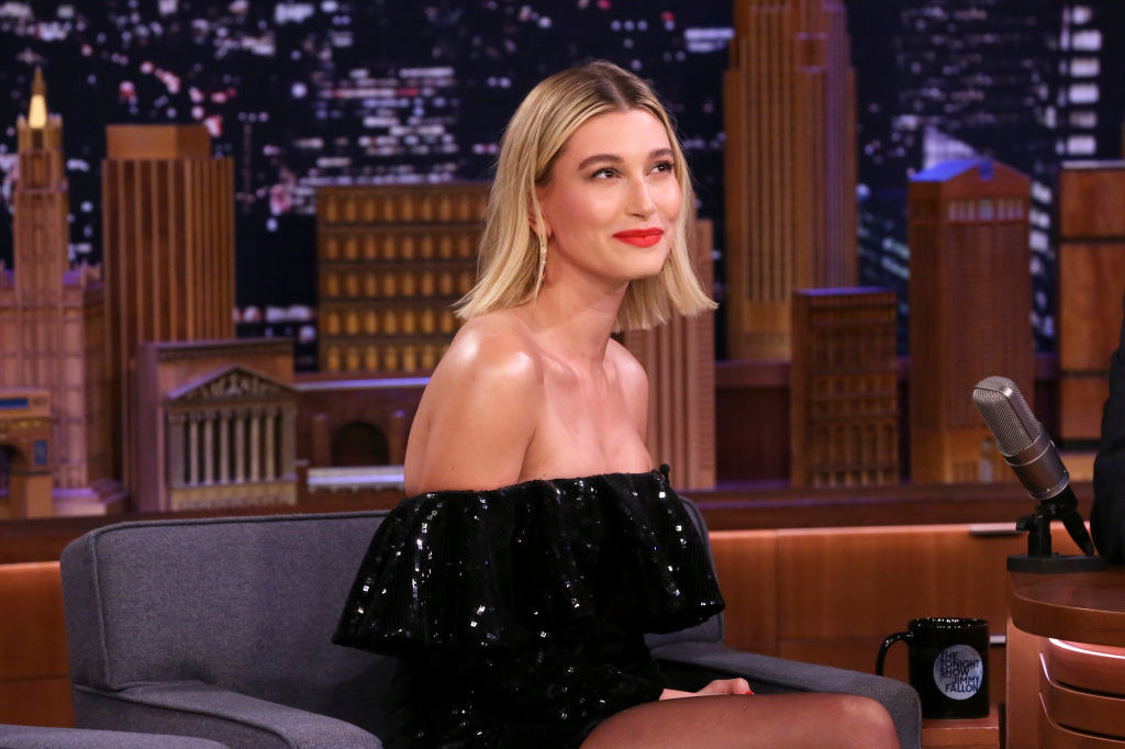 Hailey sitting during a late-night tv interview in a off-the-shoulder outfit and rocking a shoulder-length blunt cut