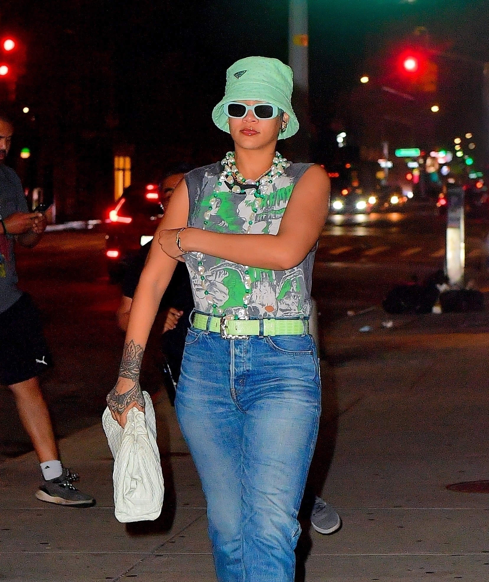 Rihanna wears a sleeveless tee tucked into high-waisted jeans and a bucket hat