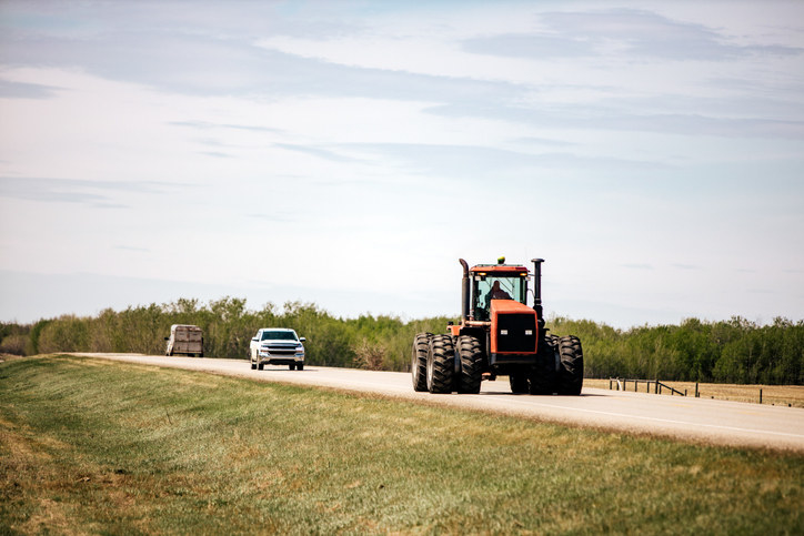 a car stuck behind a tractor on the highway
