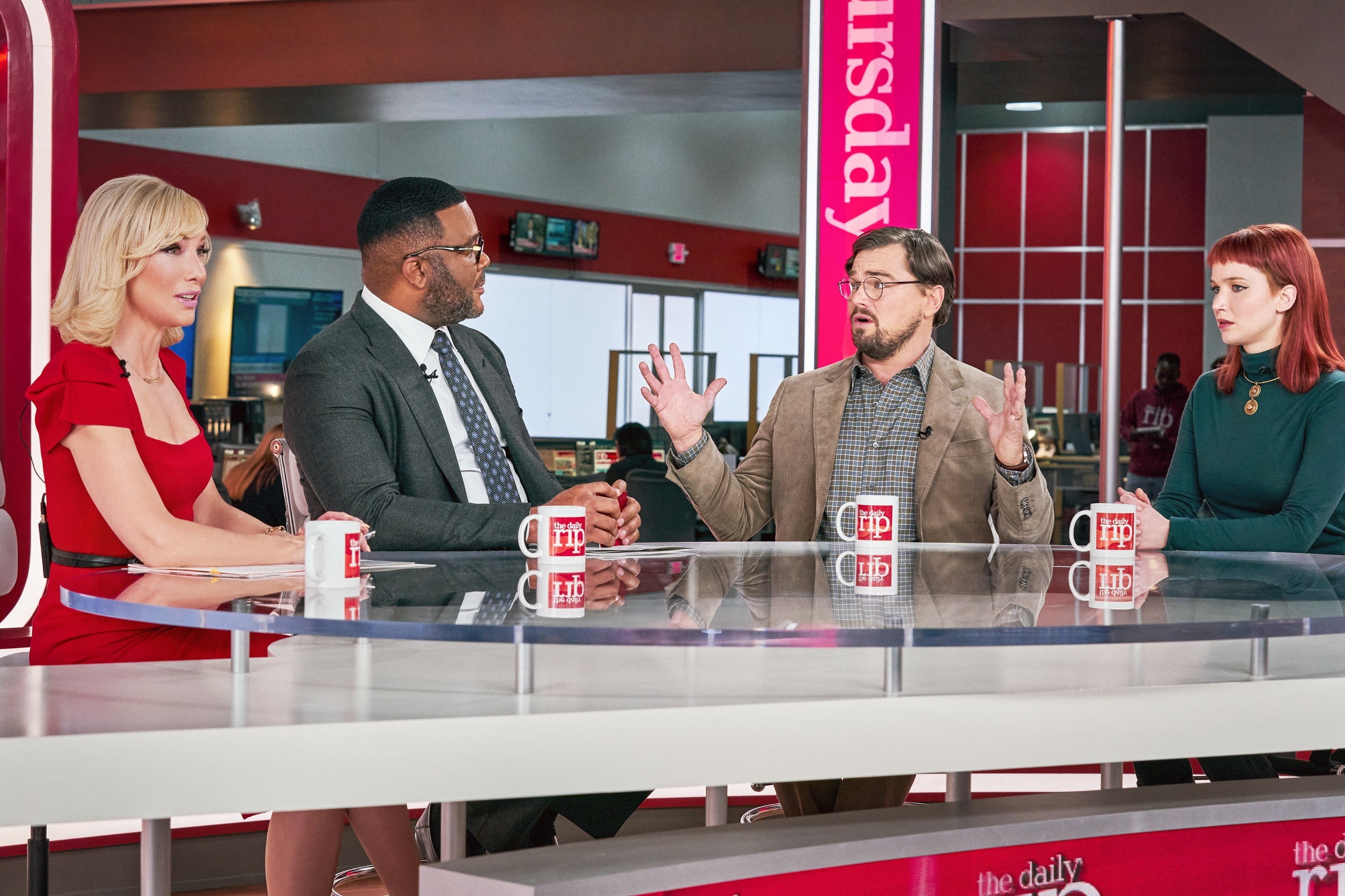 Cate Blanchett, Tyler Perry, Leonardo DiCaprio, and Jennifer Lawrence sit at a newsroom table during a live interview in a scene from the film