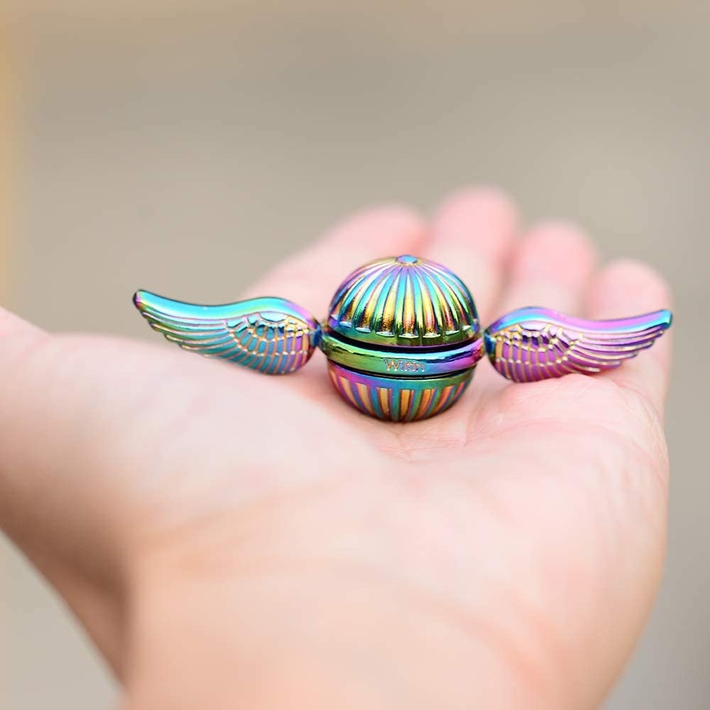 A person holding the Snitch fidget spinner in the palm of their hand