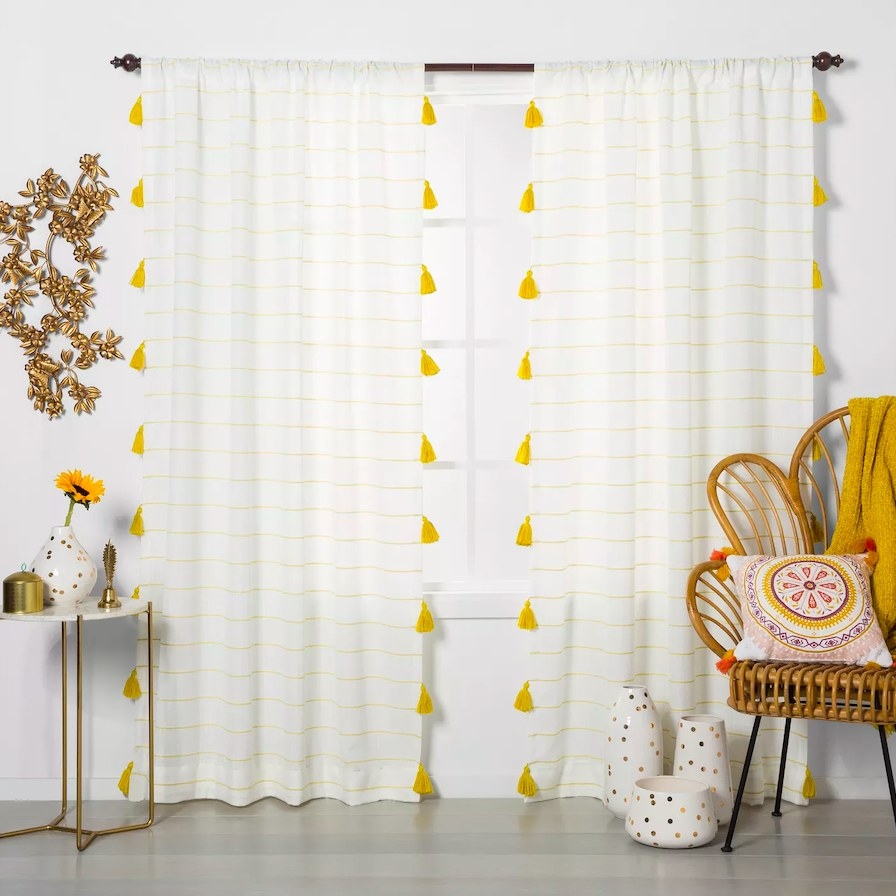 Curtain panels hanging on window next to a chair, end table and accessories