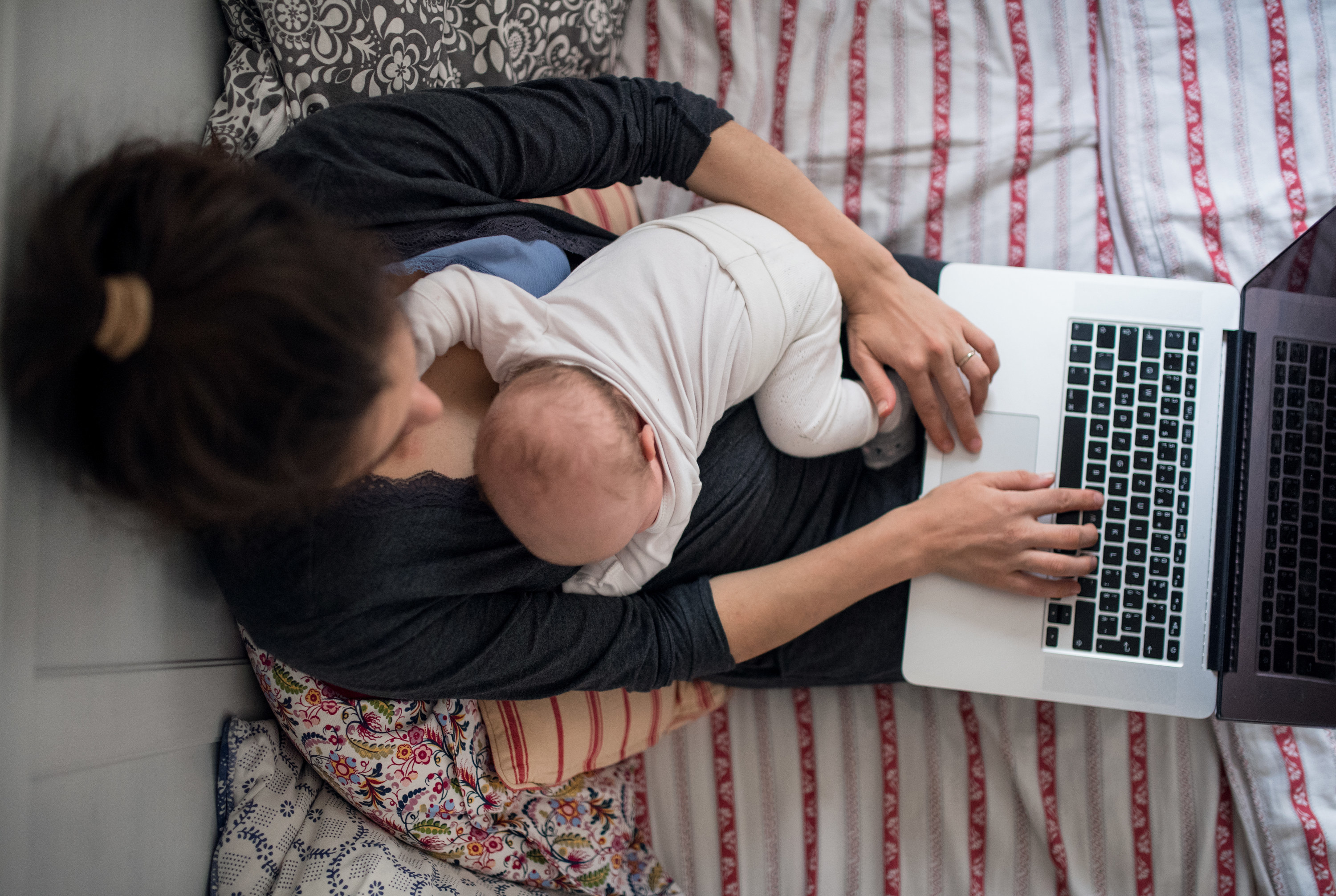 Woman holding a newborn while working from home