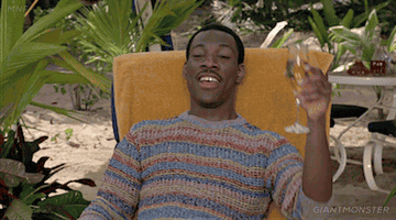 Eddie Murphy in the film &quot;Trading Places&quot;, sitting on a yellow lounge chair drinking a flute of champagne. He is on the beach and wearing a stripy jumper.