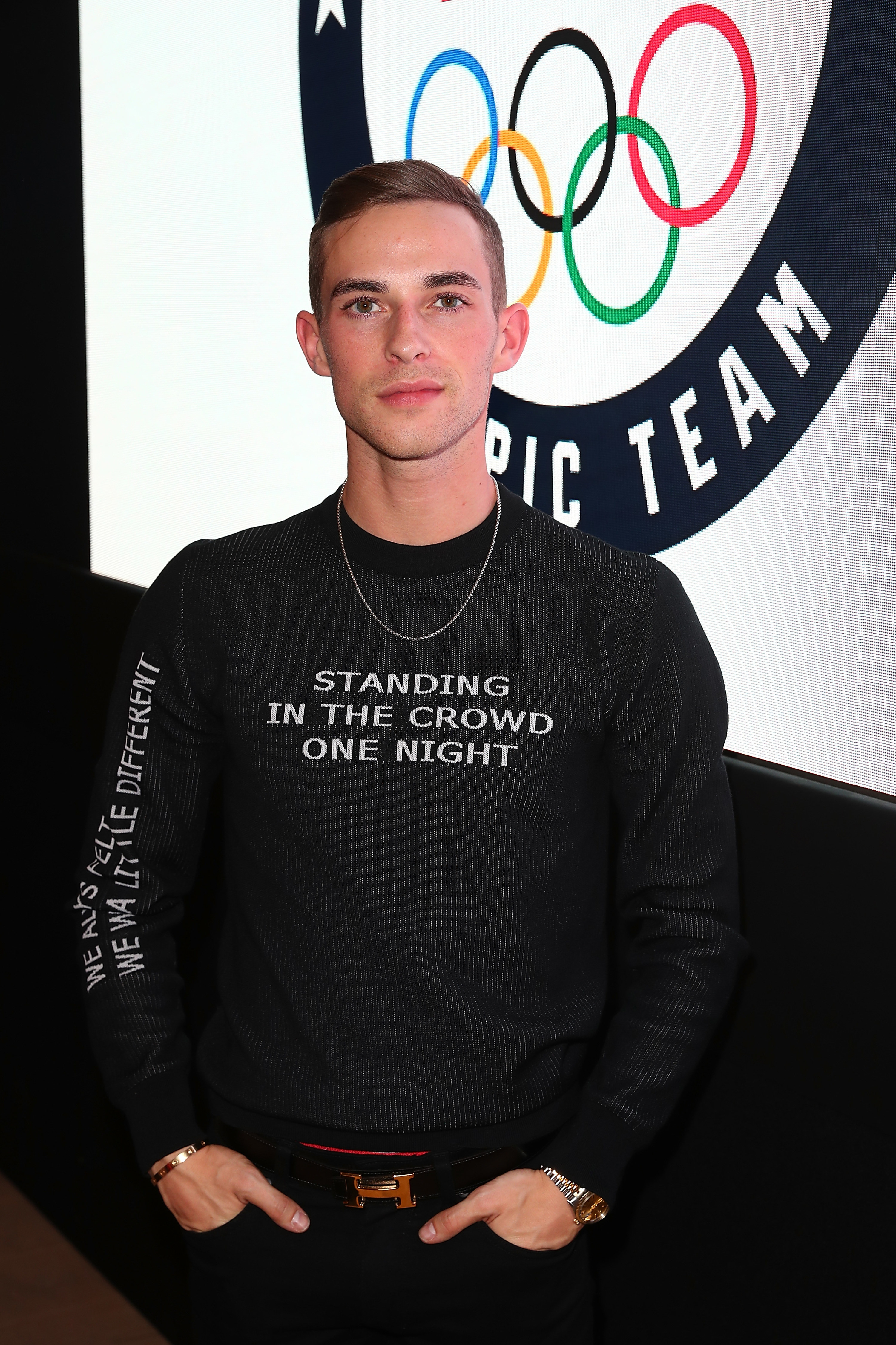 adam in front of a wall with an image of the olympic rings