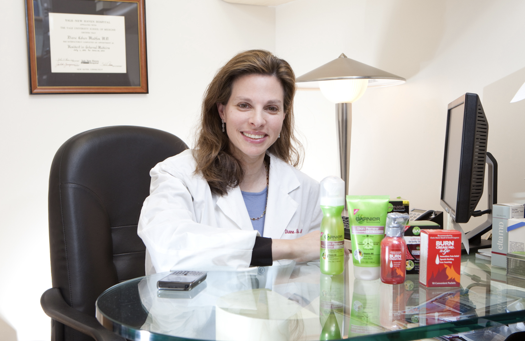 Dr. Diane Madfes sitting at her desk in her office with a white lab coat on