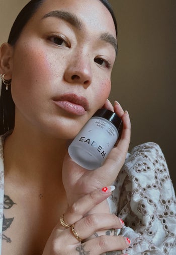 a model who used the product holding a bottle of the moisturizer