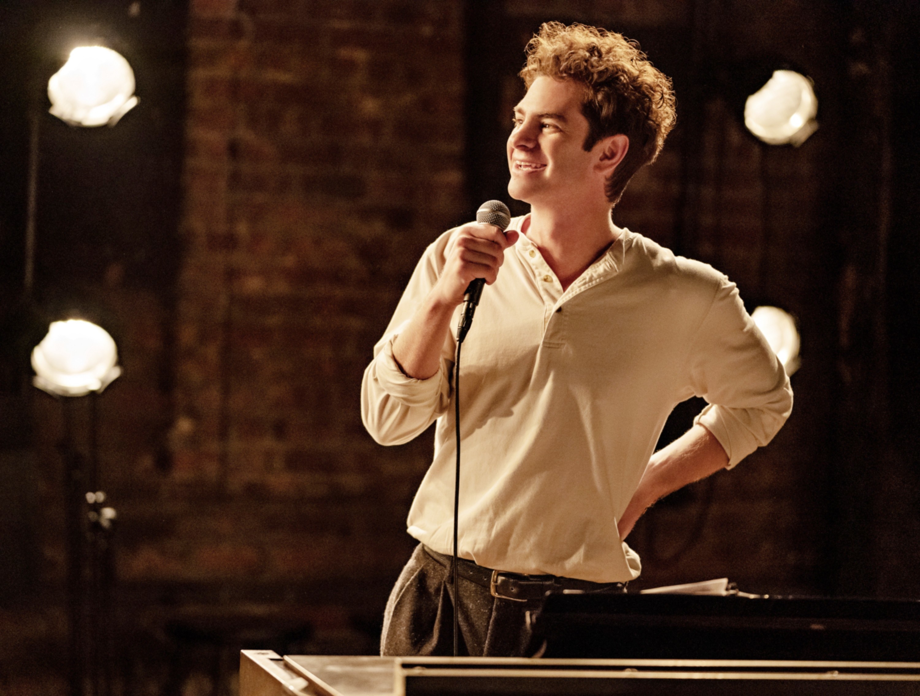 Andrew holding a mic and smiling in a scene from the film Tick, Tick...Boom!