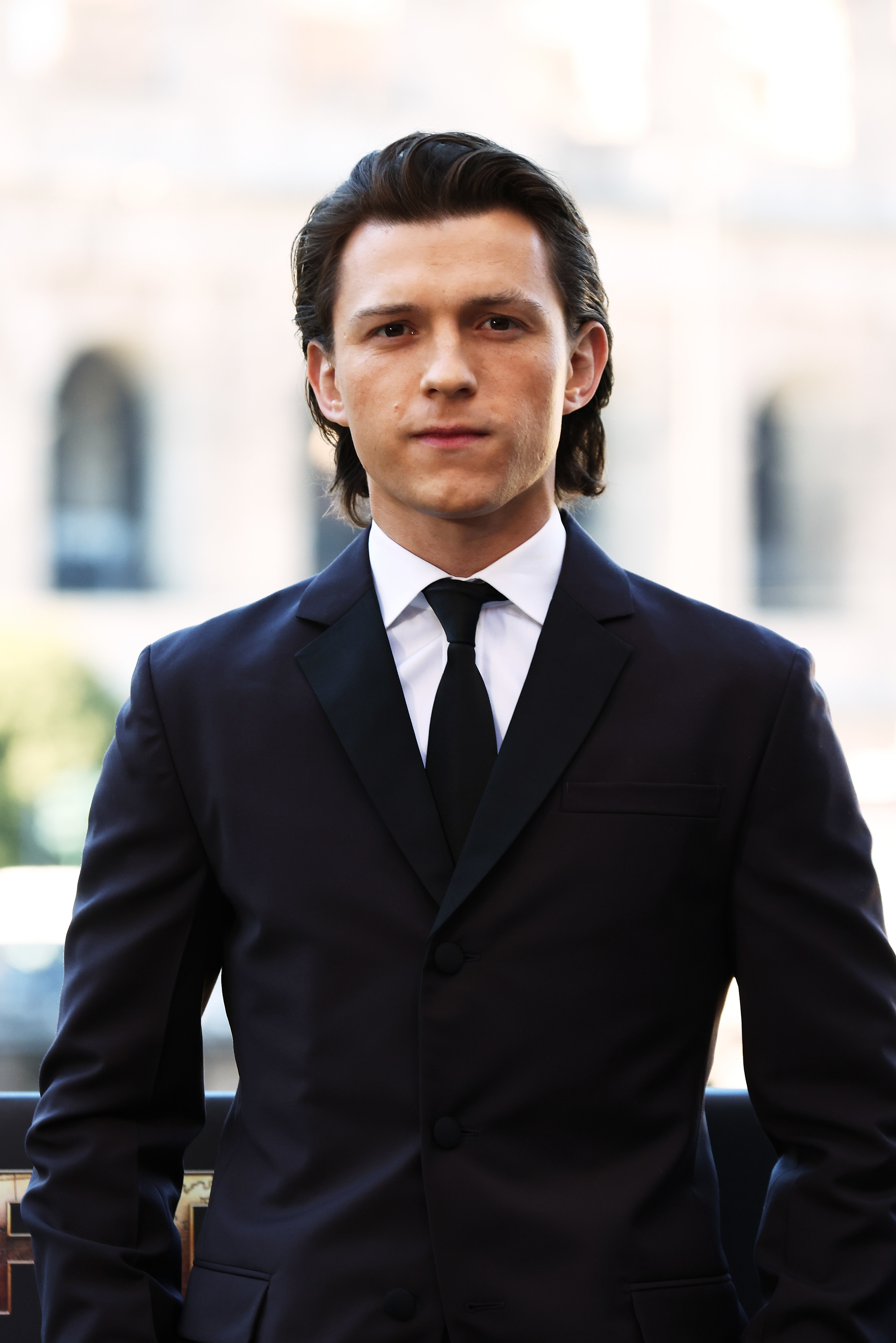 A closeup of Tom in a suit and rocking slightly longer hair than usual