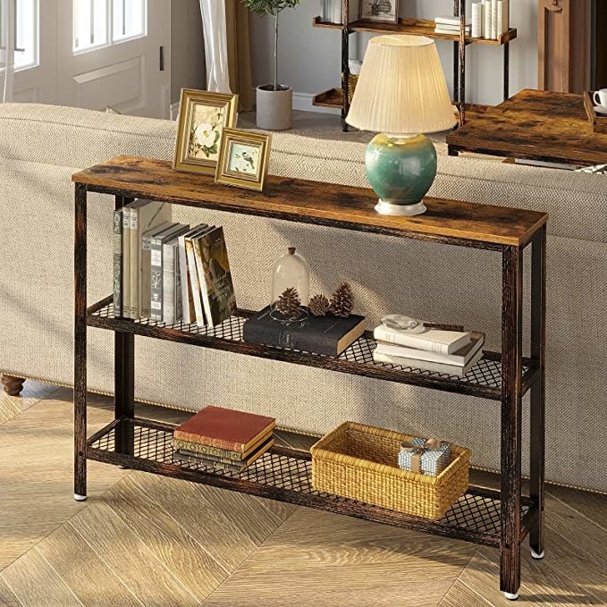 The console table holding books, a lamp, and other objects while it sits behind a couch