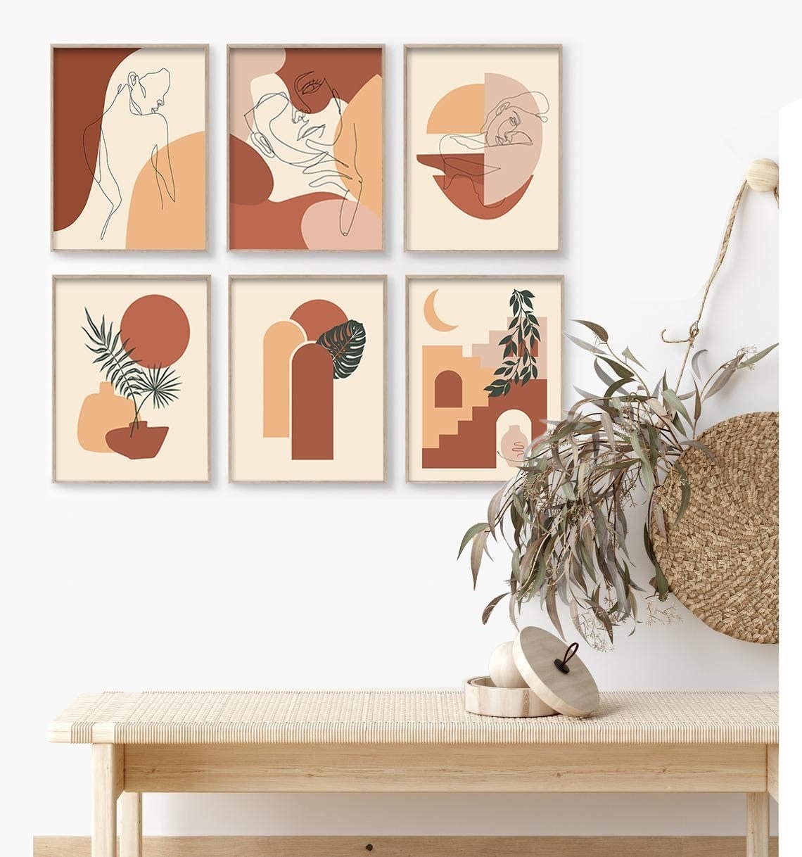 A set of six frames hanging up on a wall above a bench and a bag hanging on the wall