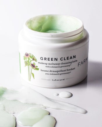 The cleansing balm with the lid off showing the green balm inside