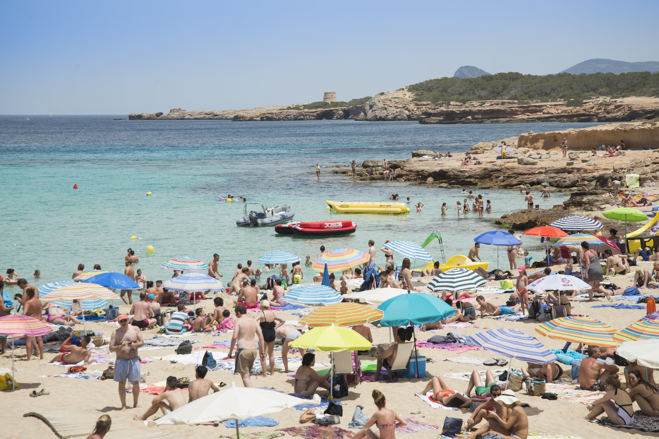 A busy beach with lots of umbrellas set up