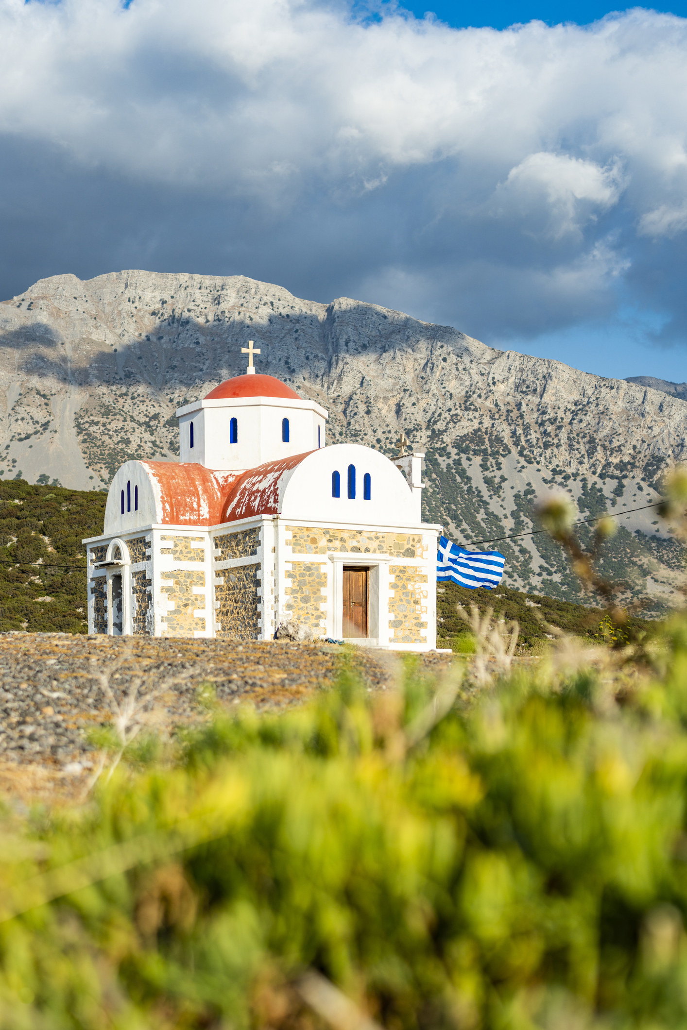 A Greek church surrounded by mountains.