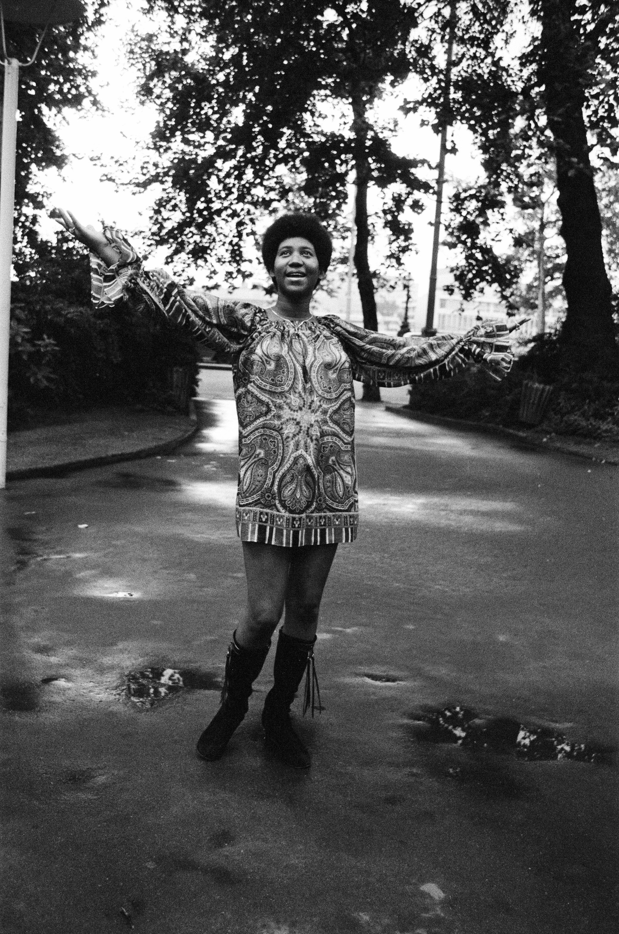 Franklin wearing a bohemian dress and tall boots, happily looking at the sky