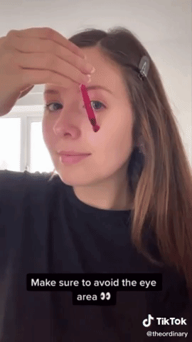 a gif of someone applying the dark red solution to their face