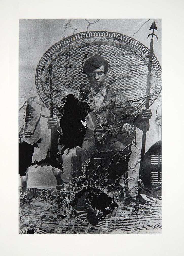 a torn and burned photo of a black panther member with a beret and spear sitting on a chair and looking at the camera
