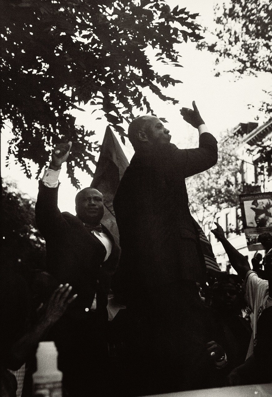 two men raising their hands as they speak to the crowd during a youth march