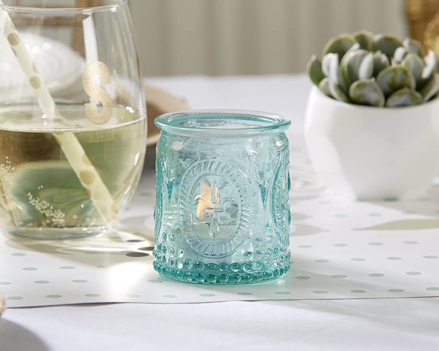 The glass tea light holder on a table with a candle in it