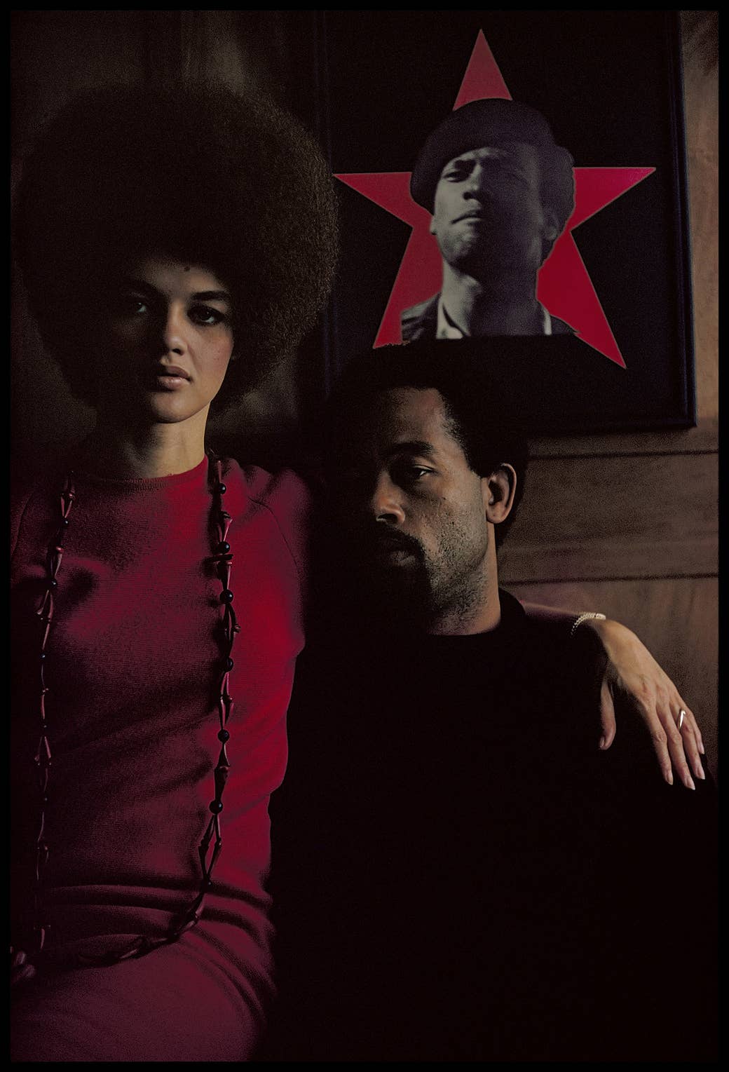 two black panthers, eldridge cleaver and his wife, in front of a poster of another black panther
