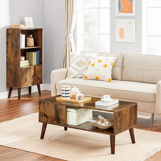 the wood coffee table in the middle of a living room in front of a couch and on top of a rug