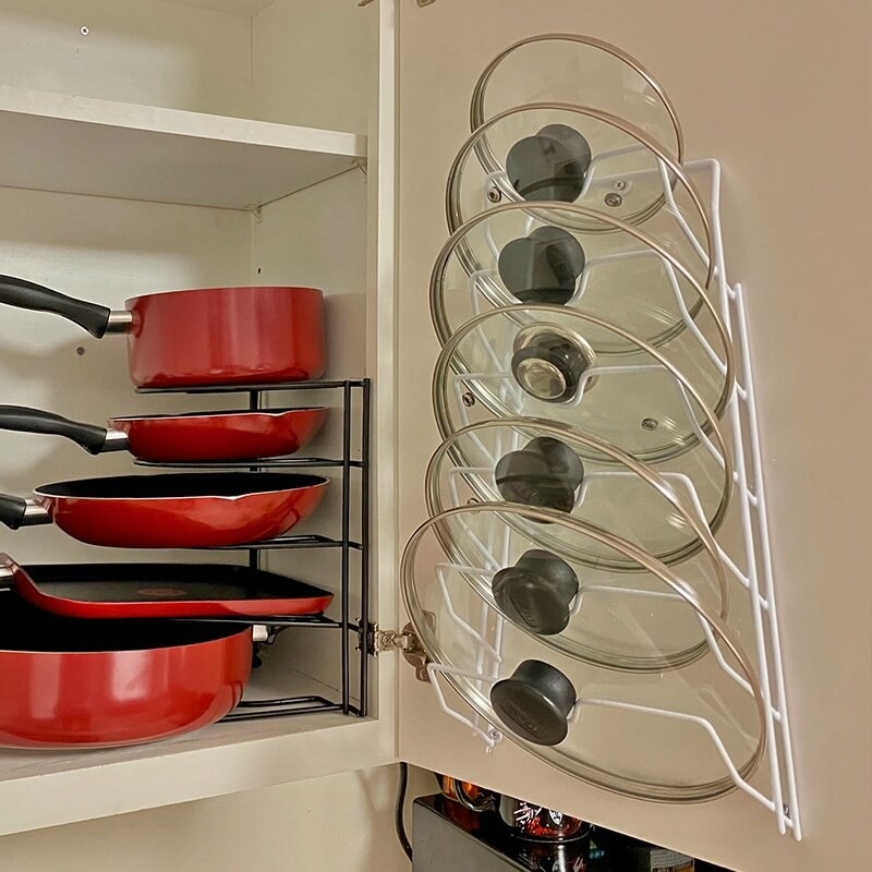 The wall mounted pot rack next to red pots and pans