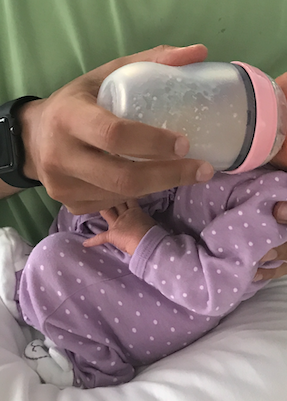 Baby drinking milk from the pink silicone bottle