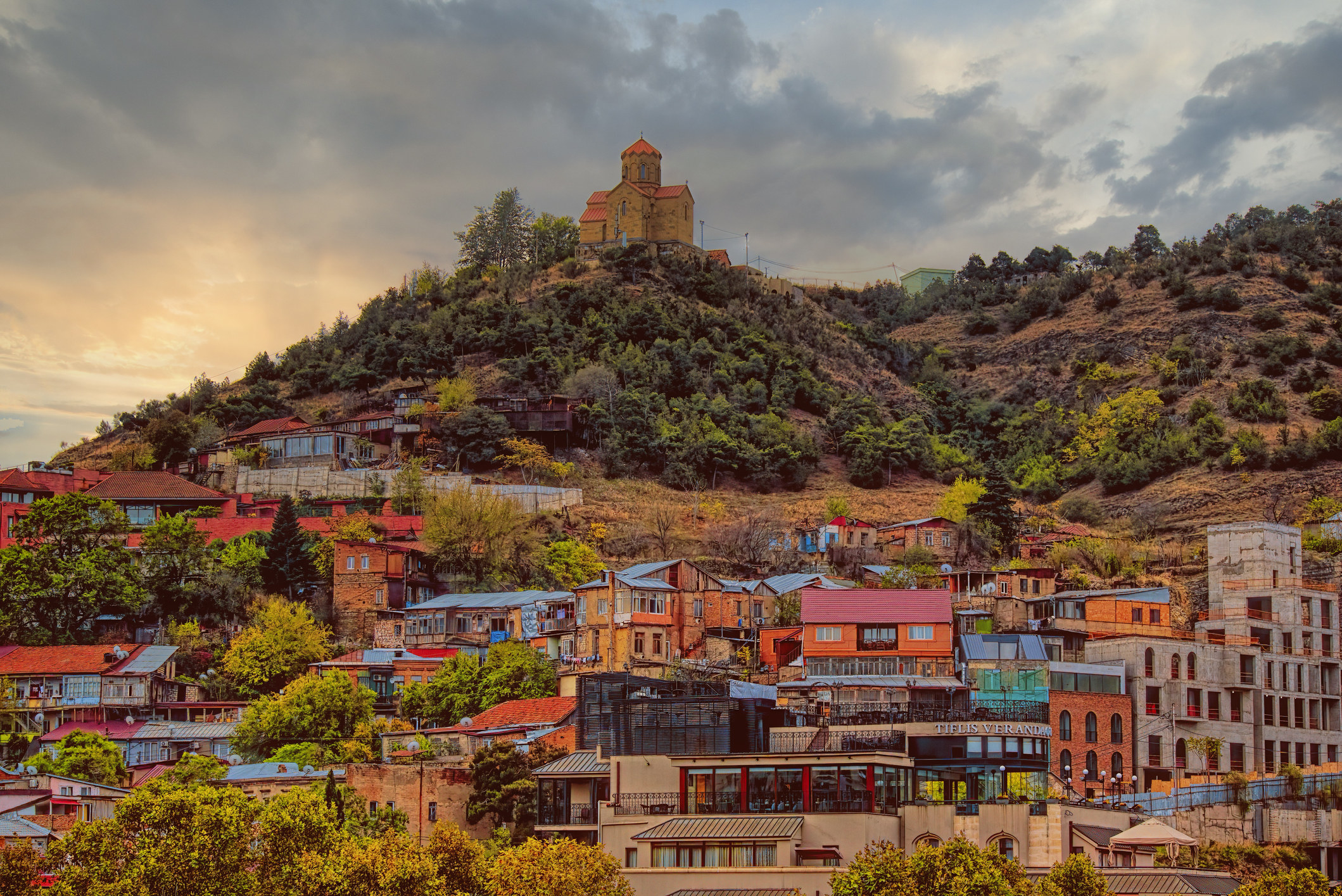 A church on a hill overlooking colorful buildings
