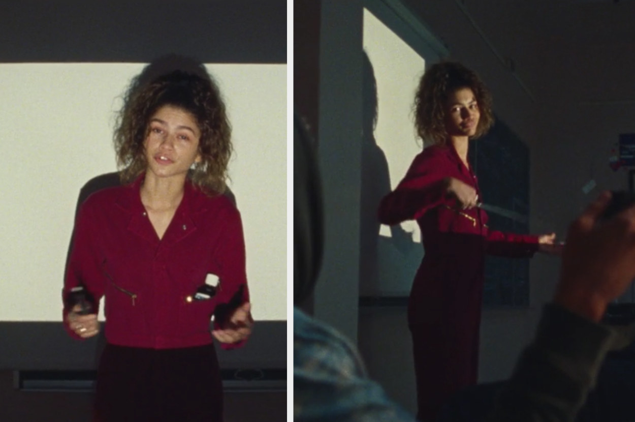 Rue stands in front of the class while wearing a maroon jumpsuit