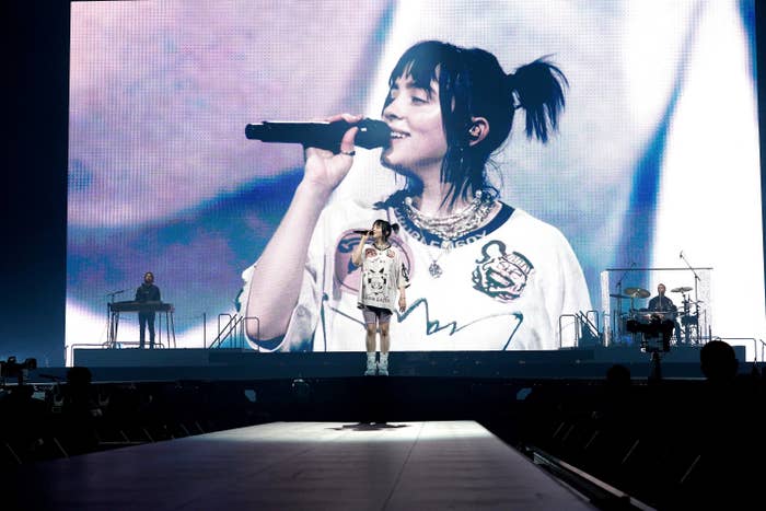 Billie performing onstage with a projection of her in the background