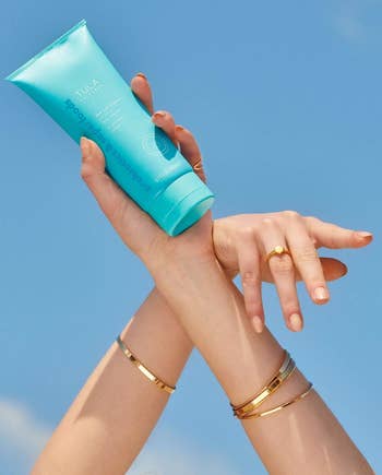 a model holding up the bright teal bottle
