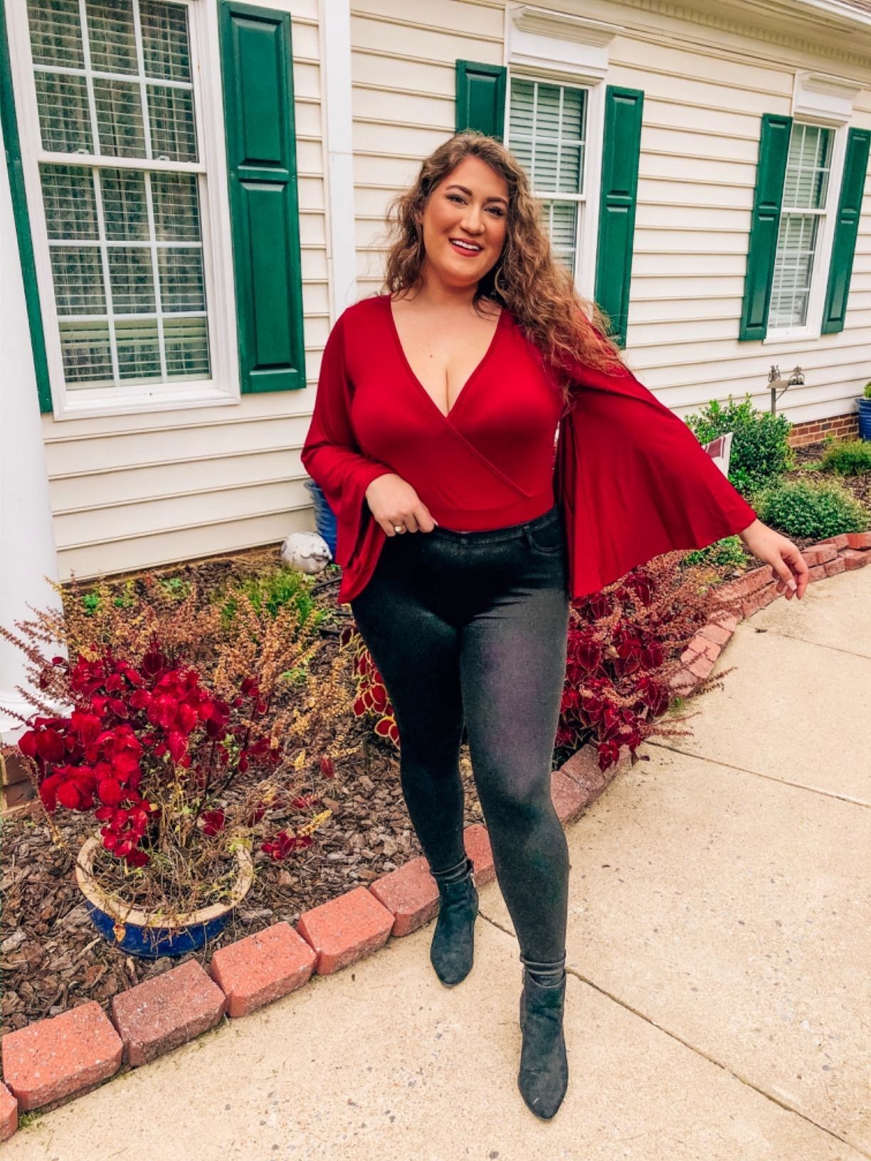Reviewer wearing the burgundy deep v-neck flare sleeve body suit